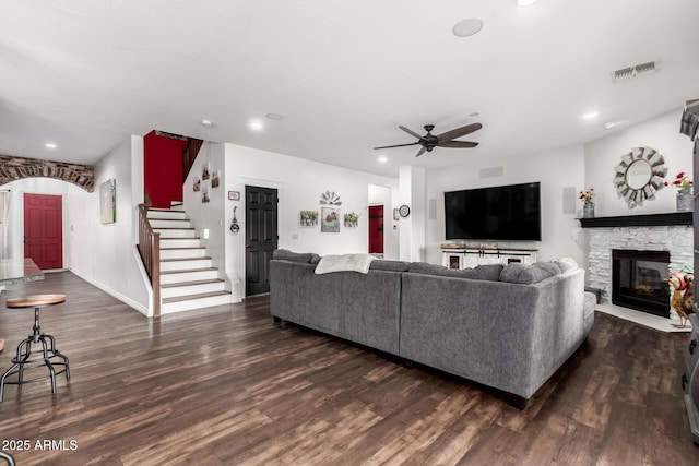 living room with ceiling fan, a fireplace, and dark wood-type flooring