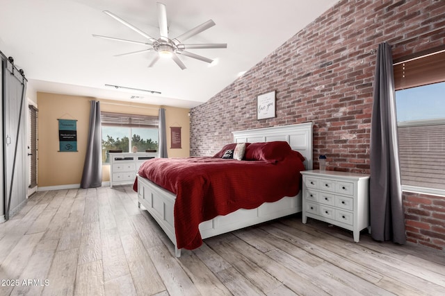 unfurnished bedroom featuring a barn door, light hardwood / wood-style floors, ceiling fan, and lofted ceiling