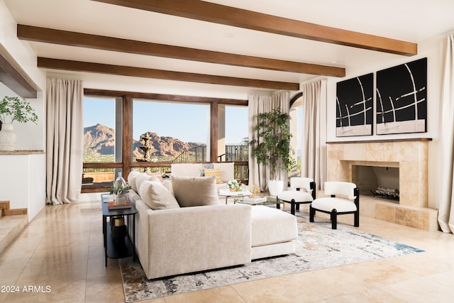 living room with a mountain view, a tiled fireplace, and beam ceiling