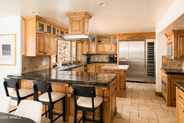 kitchen featuring built in appliances, backsplash, and kitchen peninsula