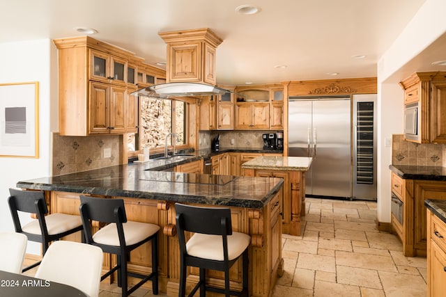 4636 E Moonlight Way, Paradise Valley, AZ 85253 - kitchen featuring built in appliances, a sink, a peninsula, stone tile flooring, and decorative backsplash