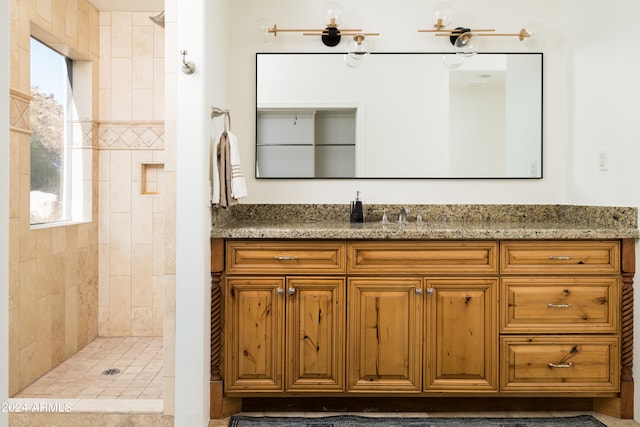 bathroom with vanity, a wealth of natural light, and tiled shower