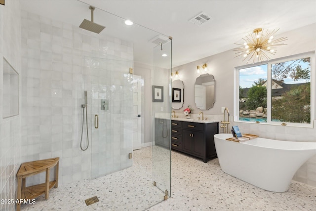 bathroom featuring speckled floor, vanity, visible vents, a soaking tub, and a shower stall