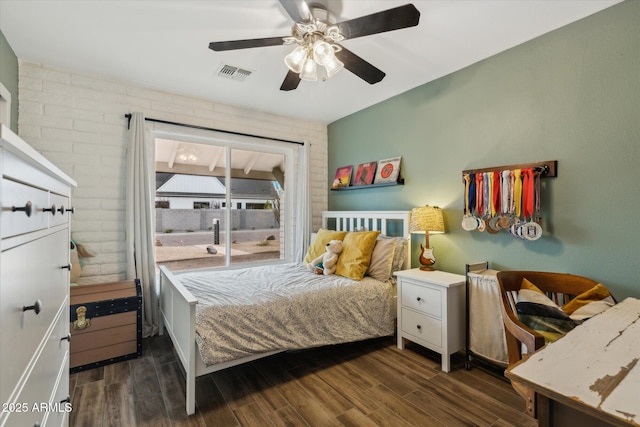 bedroom featuring brick wall, dark wood finished floors, visible vents, and a ceiling fan