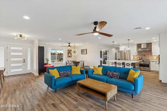 living room with recessed lighting, ceiling fan with notable chandelier, visible vents, and wood finish floors