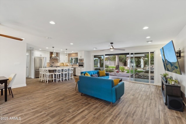 living area with ceiling fan, baseboards, wood finished floors, and recessed lighting