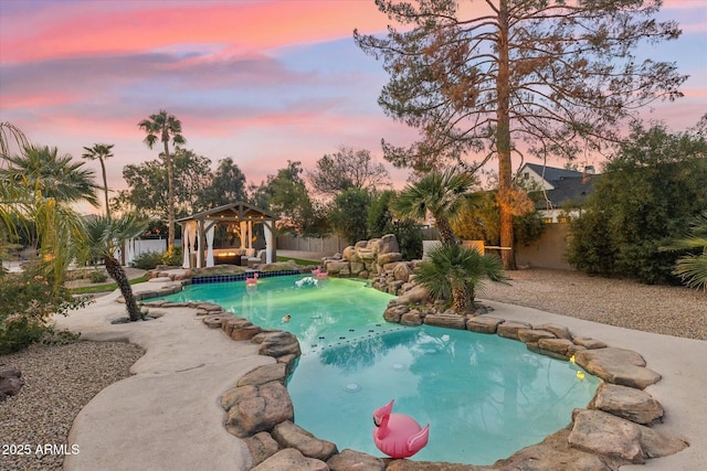 pool at dusk with a fenced backyard, a fenced in pool, and a gazebo