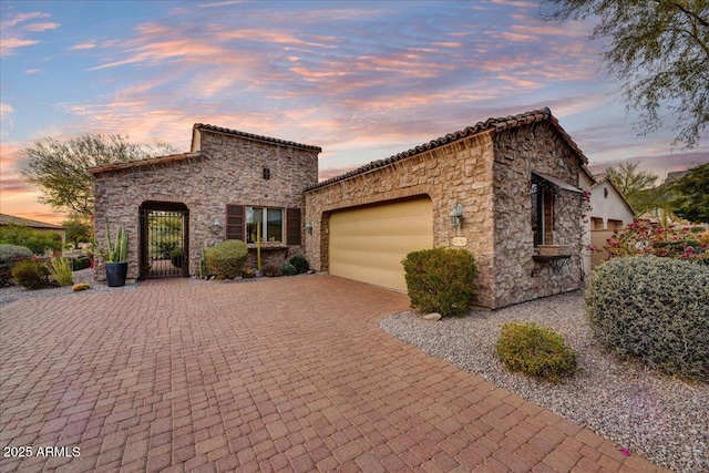 2744 S First Water Ln, Gold Canyon, AZ 85118 - mediterranean / spanish house with a tile roof, decorative driveway, stone siding, and a garage