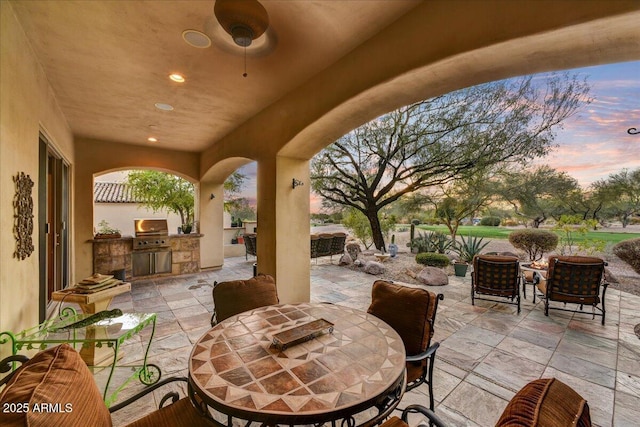 2744 S First Water Ln, Gold Canyon, AZ 85118 - patio terrace at dusk with a grill, outdoor dining area, and exterior kitchen