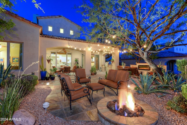 patio at twilight with an outdoor living space with a fire pit and ceiling fan