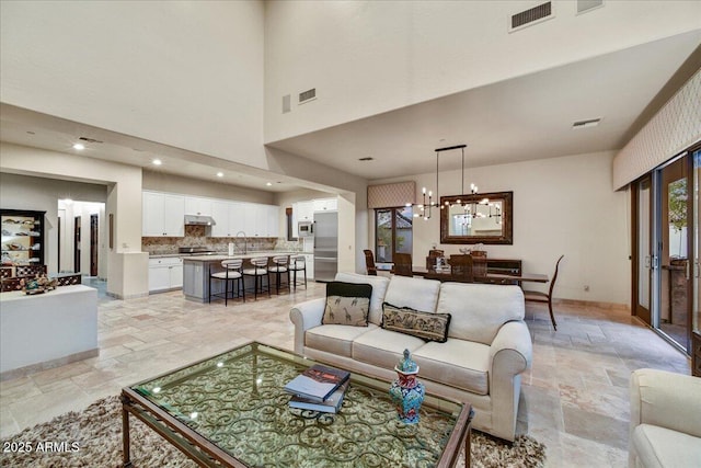 2744 S First Water Ln, Gold Canyon, AZ 85118 - living room with a high ceiling, visible vents, a chandelier, and stone tile flooring
