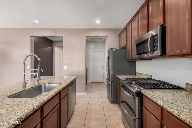 kitchen with light stone countertops, sink, light tile patterned floors, and stainless steel appliances