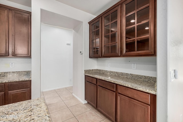 kitchen with light stone countertops, dark brown cabinetry, and light tile patterned floors