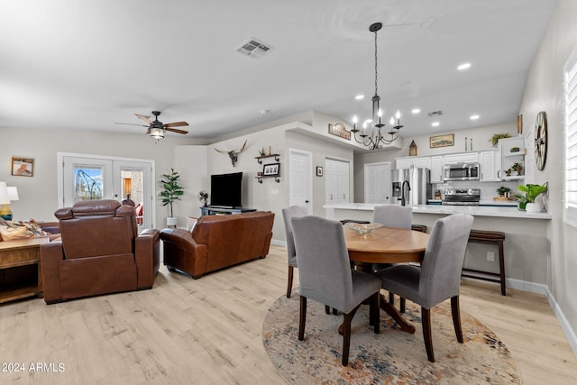 dining space with ceiling fan with notable chandelier and light hardwood / wood-style flooring