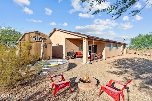 rear view of property featuring a shed, a patio, and a fire pit