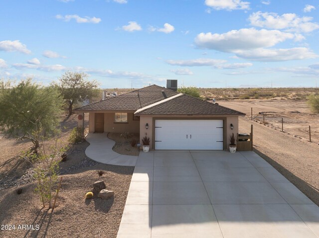 single story home featuring cooling unit and a garage