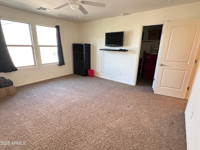 unfurnished bedroom with carpet, a walk in closet, a closet, and ceiling fan