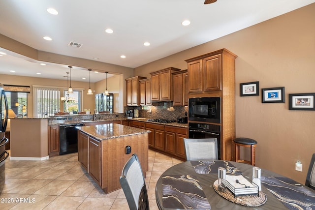 kitchen featuring a kitchen island, pendant lighting, kitchen peninsula, dark stone counters, and black appliances