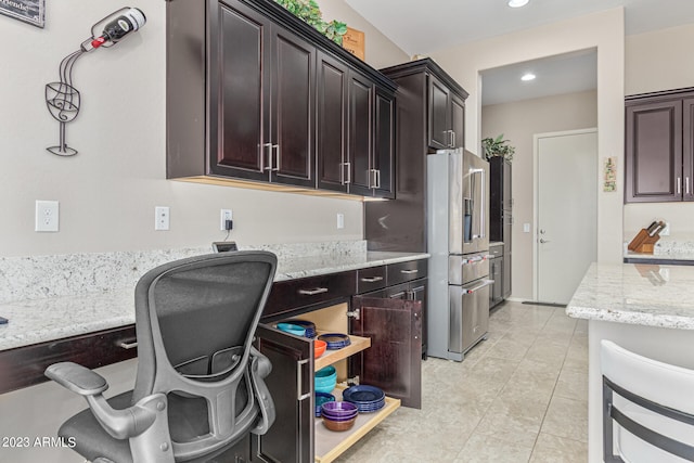 kitchen featuring high end fridge, dark brown cabinetry, light stone counters, and light tile flooring