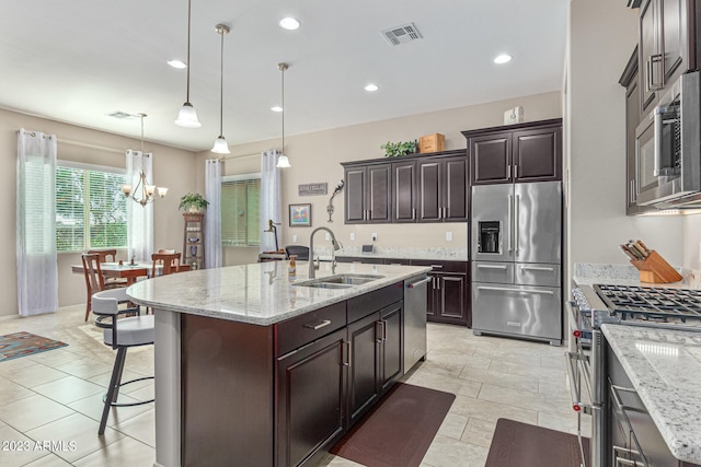 kitchen with light tile flooring, hanging light fixtures, stainless steel appliances, a notable chandelier, and sink