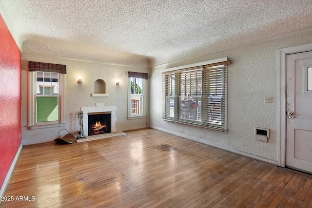 2230 N 12th St Rear, Rear, Phoenix, AZ 85006 - unfurnished living room featuring a textured wall, a textured ceiling, hardwood / wood-style floors, a fireplace with flush hearth, and healthy amount of natural light