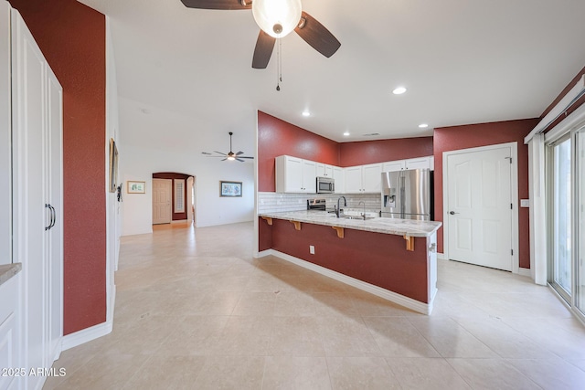 10371 W Pontiac Dr, Peoria, AZ 85382 - kitchen with stainless steel appliances, ceiling fan, a peninsula, a kitchen breakfast bar, and arched walkways