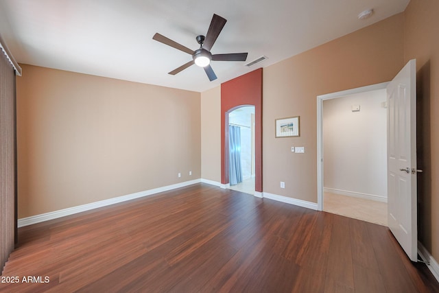 10371 W Pontiac Dr, Peoria, AZ 85382 - unfurnished bedroom with dark wood-style flooring, arched walkways, a ceiling fan, and baseboards