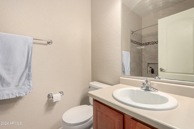 bathroom featuring toilet, vanity, and a tile shower