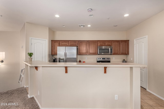 kitchen with a large island, appliances with stainless steel finishes, and a kitchen bar