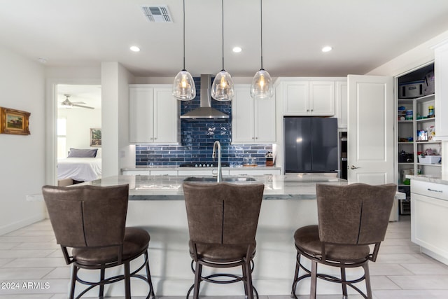 kitchen with white cabinetry, black refrigerator, decorative light fixtures, and extractor fan