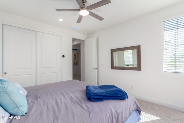 carpeted bedroom featuring ceiling fan and a closet