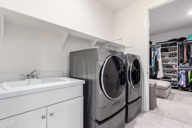 clothes washing area featuring washer and clothes dryer, cabinets, and sink