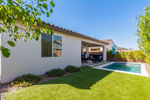 back of property with ceiling fan, an outdoor living space, a yard, and a patio area