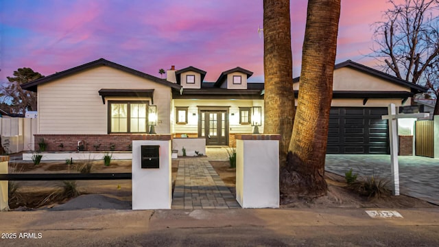 view of front of home featuring an attached garage, a fenced front yard, french doors, and brick siding