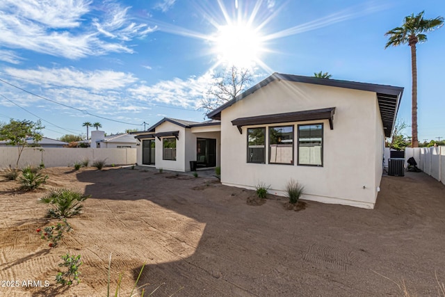 back of house featuring stucco siding, a fenced backyard, and central AC unit