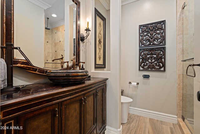 bathroom with toilet, a tile shower, crown molding, and vanity