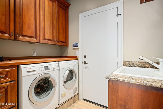 laundry room with separate washer and dryer, light wood-type flooring, cabinets, and sink