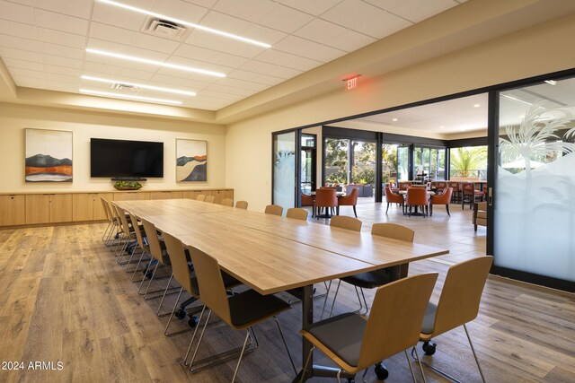 dining room featuring a tray ceiling, light hardwood / wood-style flooring, and a paneled ceiling