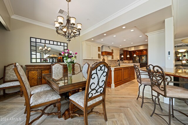 dining room featuring crown molding, a notable chandelier, and light parquet flooring