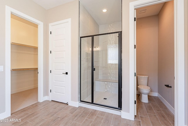 bathroom with a shower with door and toilet