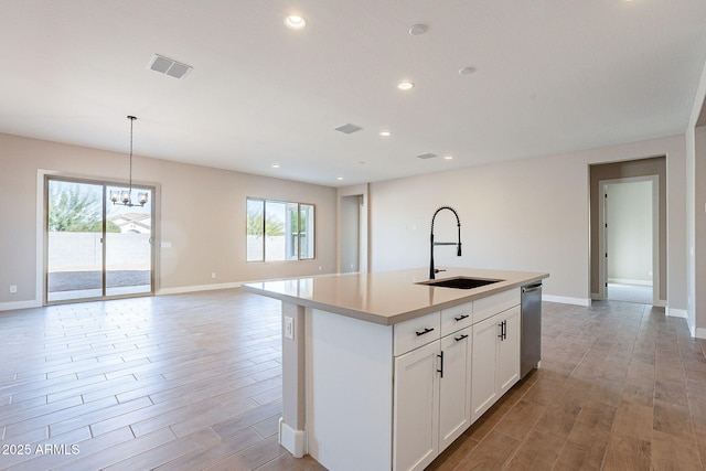 kitchen featuring sink, a kitchen island with sink, white cabinetry, decorative light fixtures, and stainless steel dishwasher