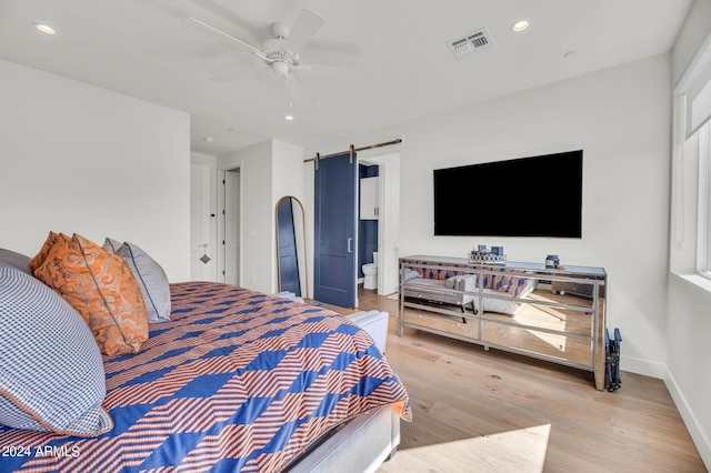 5151 N 13th Pl Unit 4, Phoenix, AZ 85014 - bedroom with a barn door, wood finished floors, ceiling fan, connected bathroom, and baseboards