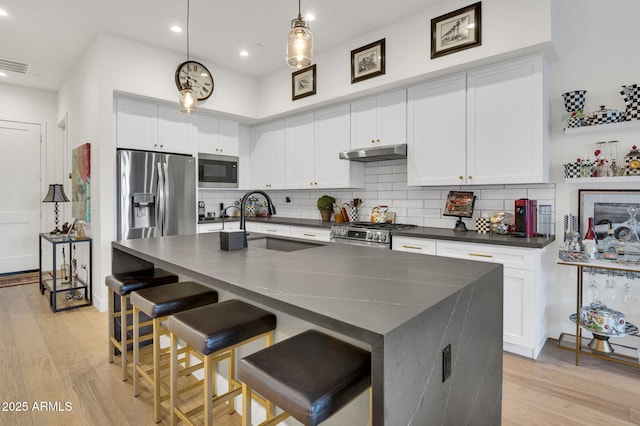 5151 N 13th Pl Unit 4, Phoenix, AZ 85014 - kitchen featuring stainless steel appliances, under cabinet range hood, dark countertops, a sink, and light wood-type flooring