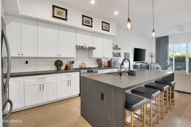 5151 N 13th Pl Unit 4, Phoenix, AZ 85014 - kitchen with a sink, open floor plan, under cabinet range hood, stainless steel range with gas stovetop, and tasteful backsplash