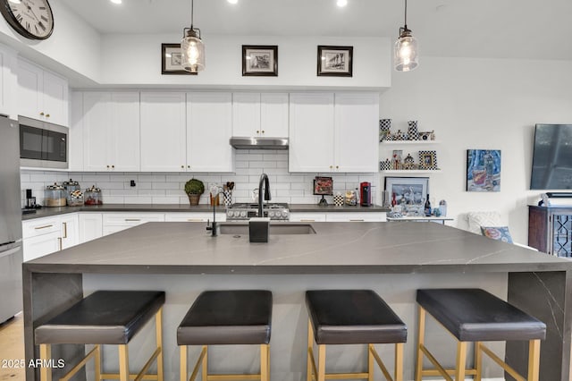 5151 N 13th Pl Unit 4, Phoenix, AZ 85014 - kitchen with dark countertops, stainless steel appliances, a sink, backsplash, and under cabinet range hood
