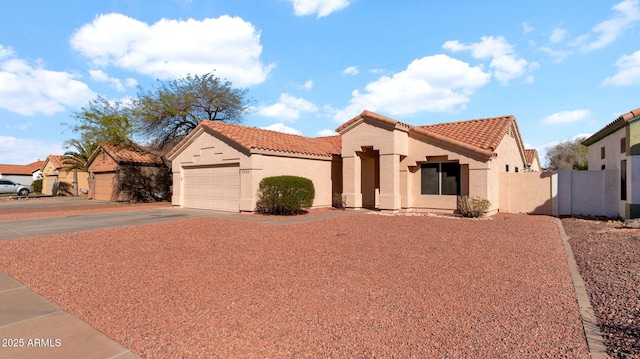 mediterranean / spanish-style home featuring driveway, a garage, a tile roof, fence, and stucco siding