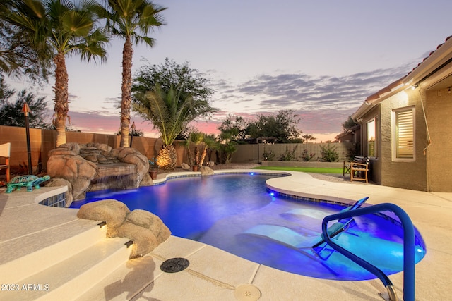 pool at dusk with pool water feature and a patio