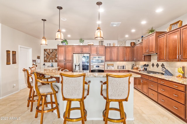 kitchen with stainless steel appliances, pendant lighting, light stone counters, and a spacious island