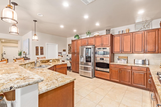 kitchen featuring a large island with sink, light stone countertops, sink, pendant lighting, and appliances with stainless steel finishes