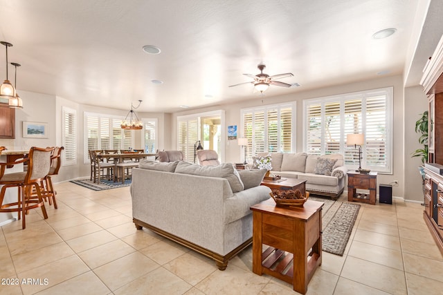 tiled living room with ceiling fan with notable chandelier and a wealth of natural light